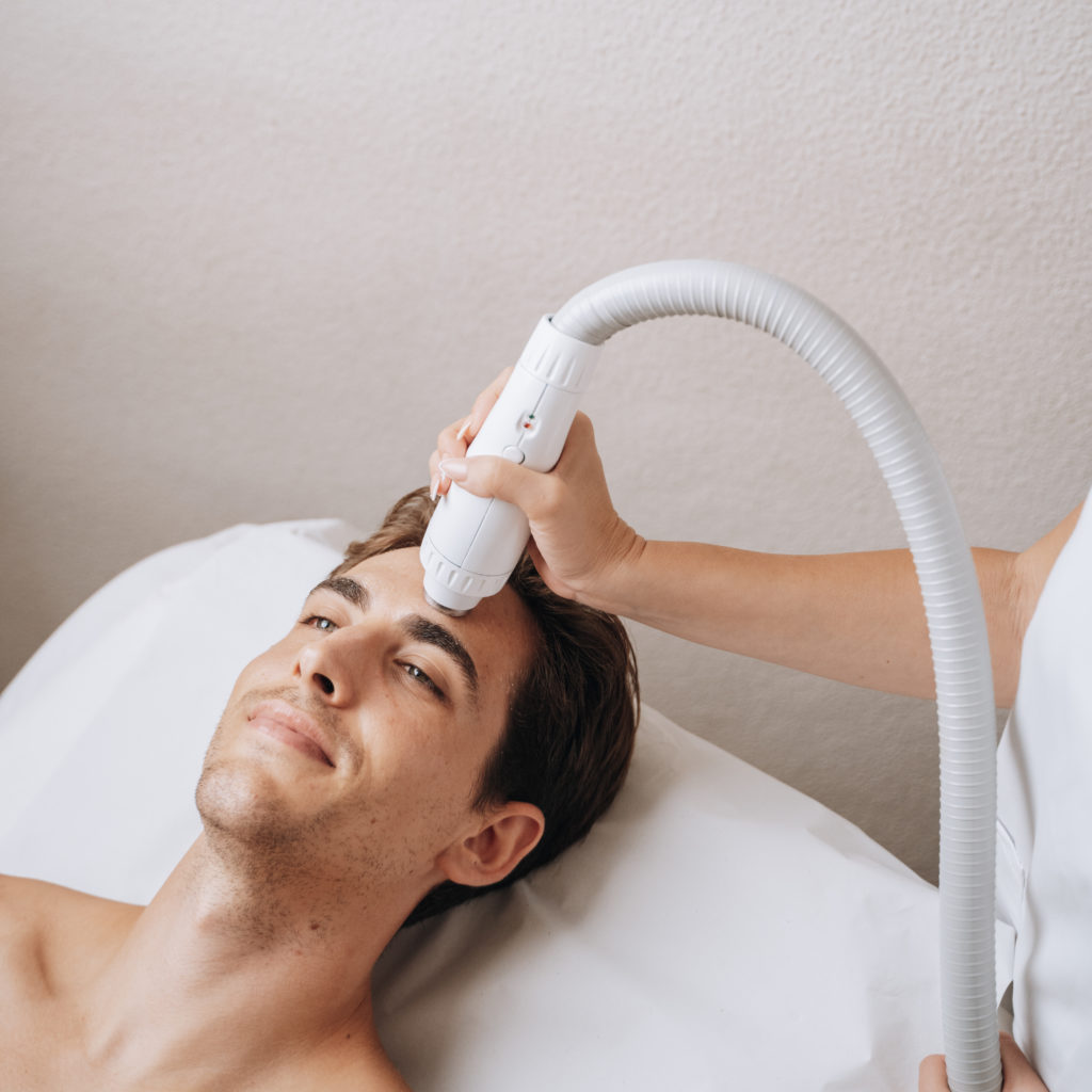 Hombre recibiendo tratamiento con máquina de radiofrecuencia de Adermica en la zona facial.